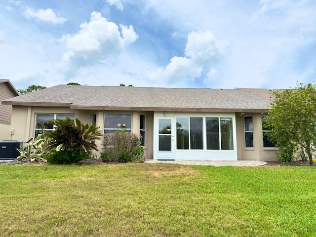 back of house with stucco siding, a yard, central AC unit, roof with shingles, and a garage
