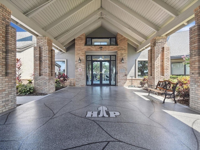 view of exterior entry featuring french doors, stucco siding, and brick siding