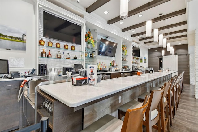 community bar area featuring wood finished floors, beam ceiling, hanging light fixtures, recessed lighting, and a barn door