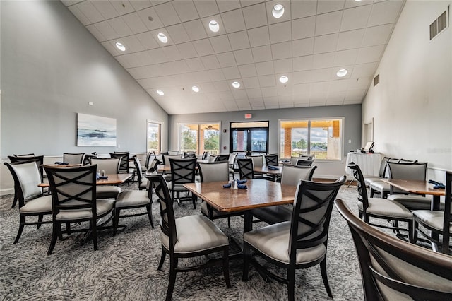 carpeted dining space with healthy amount of natural light, recessed lighting, high vaulted ceiling, and baseboards