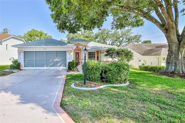 single story home featuring stucco siding, concrete driveway, an attached garage, and a front yard