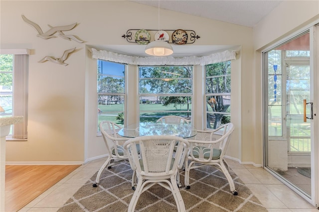 tiled dining room with lofted ceiling, healthy amount of natural light, and baseboards