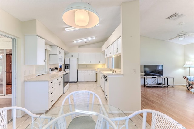 kitchen with white appliances, light countertops, white cabinetry, lofted ceiling, and a sink