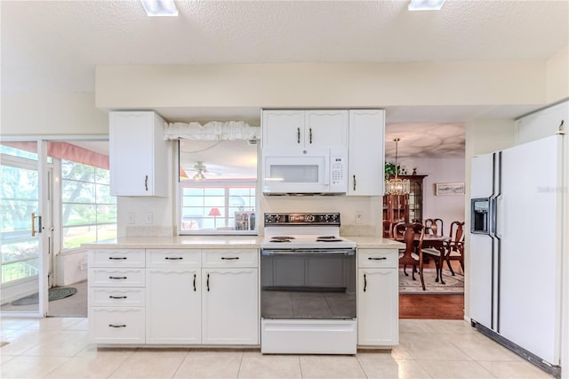 kitchen with white appliances, white cabinets, light countertops, healthy amount of natural light, and a textured ceiling