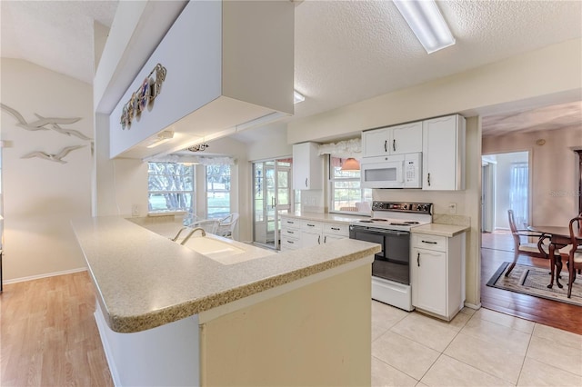 kitchen with electric range, white microwave, a peninsula, light countertops, and a textured ceiling