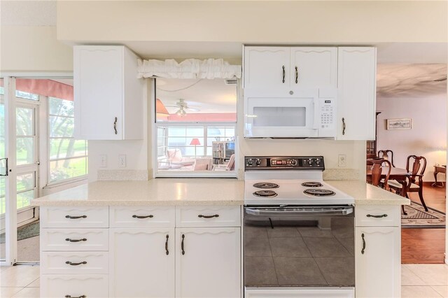 kitchen featuring white appliances, plenty of natural light, and white cabinetry