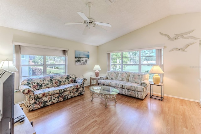 living room with vaulted ceiling, a ceiling fan, wood finished floors, baseboards, and a textured ceiling