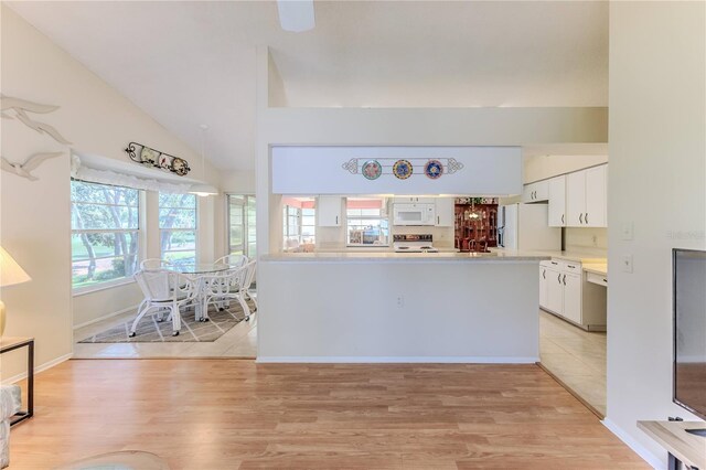 kitchen featuring white appliances, white cabinetry, light wood finished floors, light countertops, and vaulted ceiling