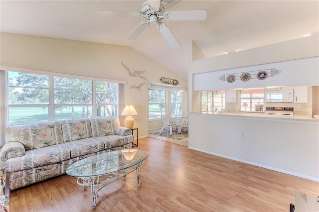 living area featuring light wood-style floors, vaulted ceiling, a ceiling fan, and baseboards