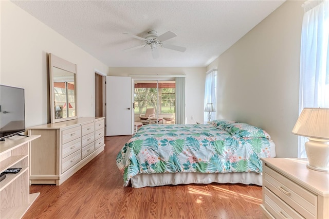 bedroom featuring access to outside, light wood finished floors, a textured ceiling, and a ceiling fan