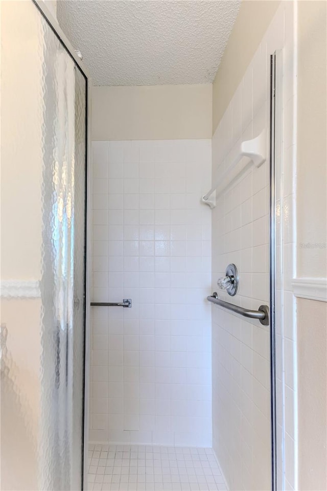 full bathroom featuring a shower stall and a textured ceiling