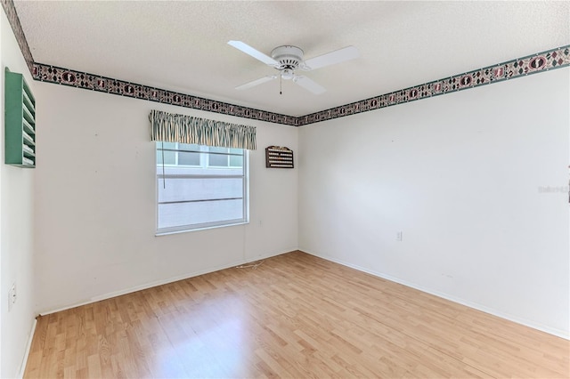 spare room featuring wood finished floors, ceiling fan, baseboards, and a textured ceiling