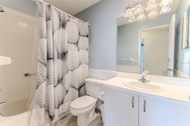 bathroom with toilet, vanity, shower / bath combo with shower curtain, tile patterned flooring, and a wainscoted wall
