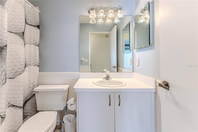 half bath featuring a wainscoted wall, toilet, and vanity