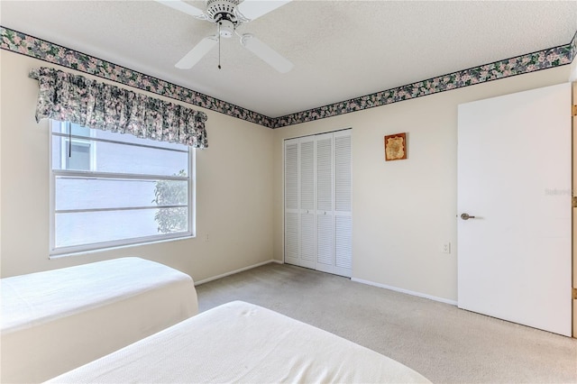 unfurnished bedroom with carpet, a closet, a ceiling fan, and baseboards