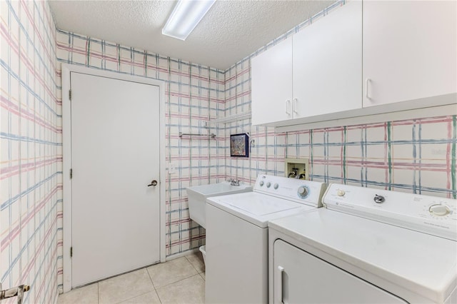washroom featuring wallpapered walls, washer and dryer, cabinet space, a textured ceiling, and light tile patterned flooring