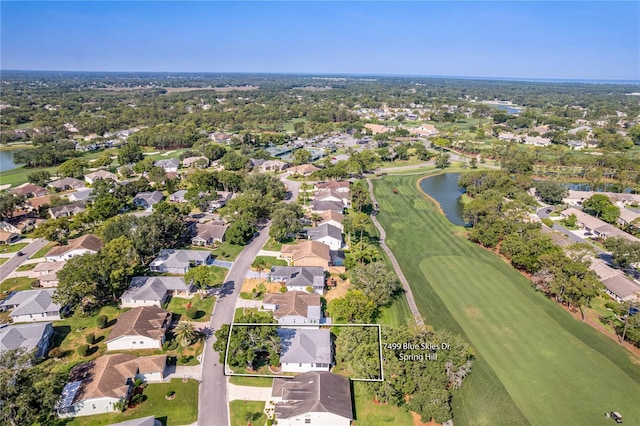 aerial view of property and surrounding area featuring nearby suburban area, a local golf course, a nearby body of water, and property parcel outlined