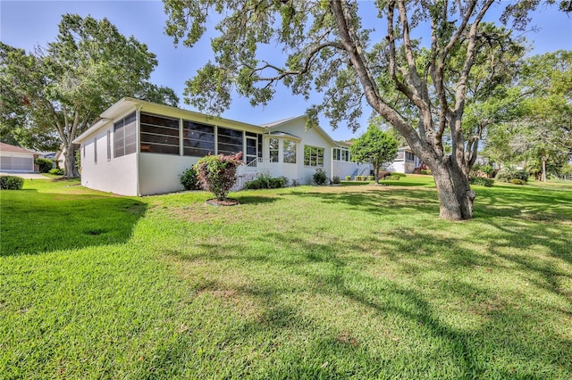 rear view of property featuring a sunroom and a yard