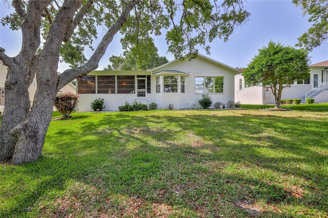 view of front of property featuring a sunroom and a front lawn