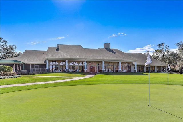 back of property with a putting green, a yard, and a chimney