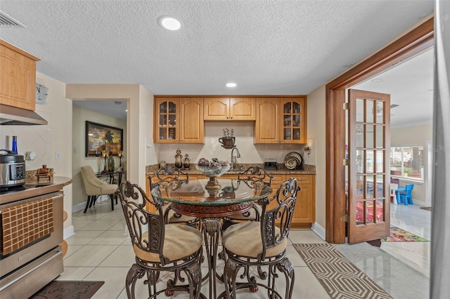dining space with a textured ceiling, light tile patterned floors, baseboards, and recessed lighting
