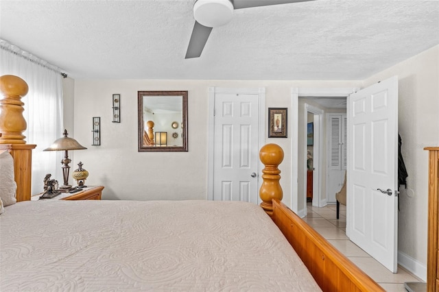 bedroom with a textured ceiling, ceiling fan, light tile patterned flooring, and baseboards