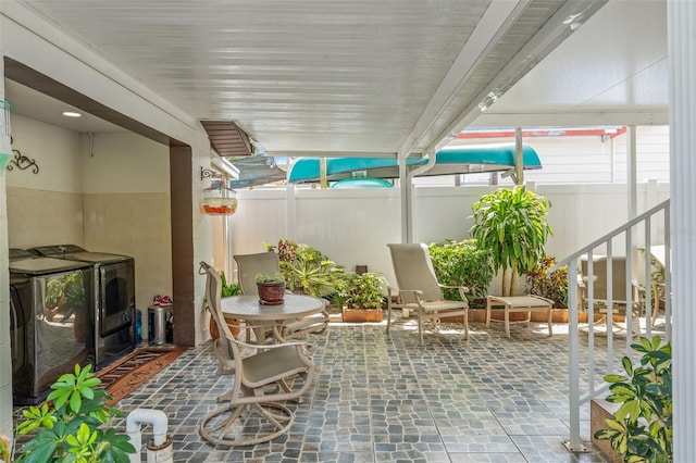 view of patio featuring washing machine and clothes dryer and fence