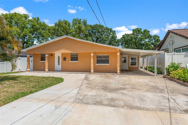 view of front facade with stucco siding, driveway, and a carport