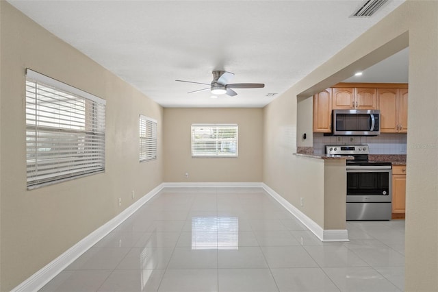 kitchen with stainless steel appliances, decorative backsplash, a ceiling fan, light tile patterned floors, and baseboards