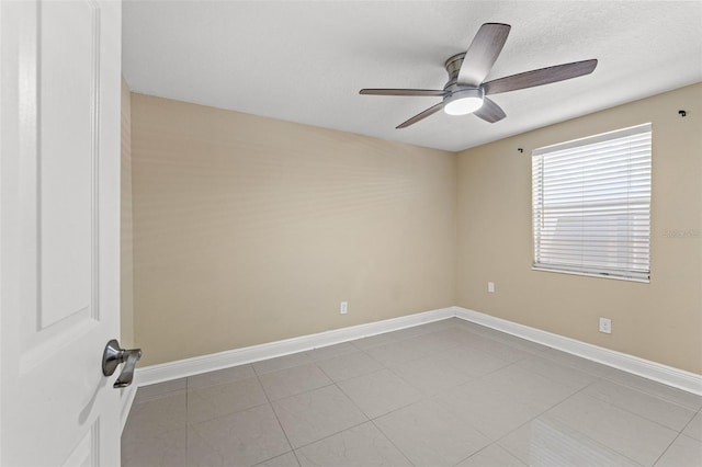 tiled spare room with a ceiling fan, baseboards, and a textured ceiling