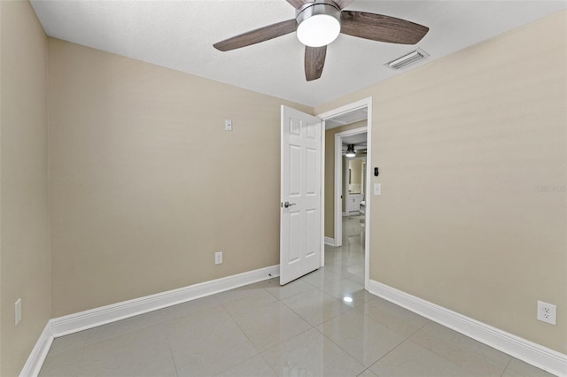 empty room with ceiling fan, baseboards, and light tile patterned flooring