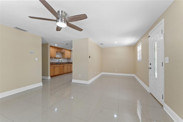 empty room featuring light tile patterned floors, baseboards, a ceiling fan, a sink, and recessed lighting
