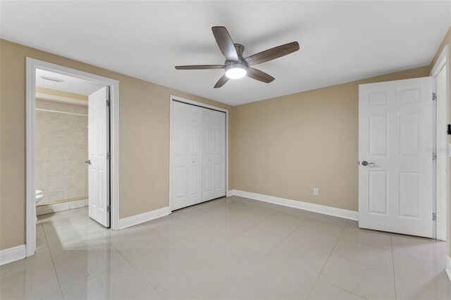 unfurnished bedroom featuring baseboards, light tile patterned floors, ceiling fan, connected bathroom, and a closet