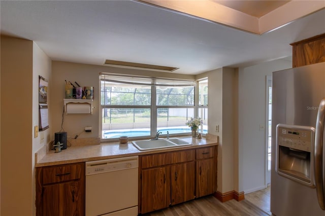 8126 Wooden Dr, Spring Hill, FL 34606 - kitchen featuring stainless steel fridge with ice dispenser, white dishwasher, a sink, light wood-type flooring, and light countertops
