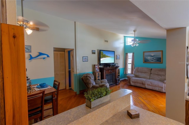 8126 Wooden Dr, Spring Hill, FL 34606 - living area featuring ceiling fan, wood finished floors, a glass covered fireplace, and high vaulted ceiling