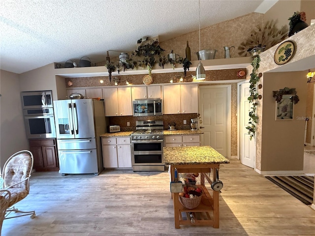9311 Haas Dr, Hudson, FL 34669 - kitchen with stainless steel appliances, lofted ceiling, light wood-style floors, decorative backsplash, and a textured ceiling