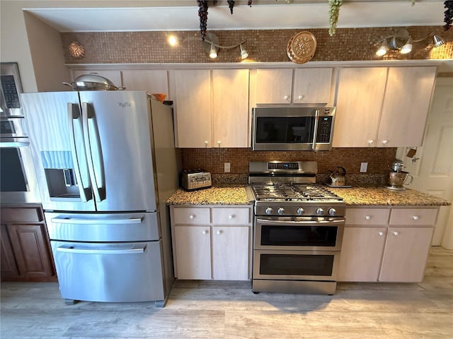 9311 Haas Dr, Hudson, FL 34669 - kitchen featuring appliances with stainless steel finishes, decorative backsplash, light stone counters, and light wood-type flooring