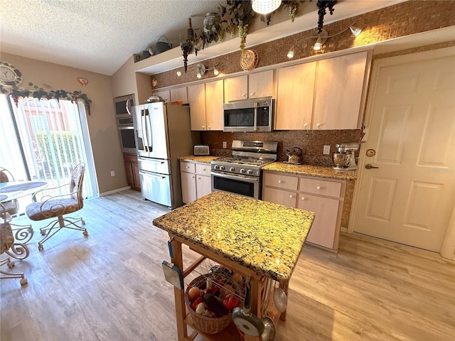 9311 Haas Dr, Hudson, FL 34669 - kitchen with appliances with stainless steel finishes, lofted ceiling, tasteful backsplash, light wood-type flooring, and a textured ceiling