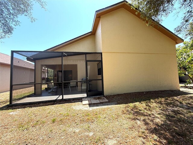 9311 Haas Dr, Hudson, FL 34669 - rear view of property featuring stucco siding, a patio area, a lawn, and a lanai