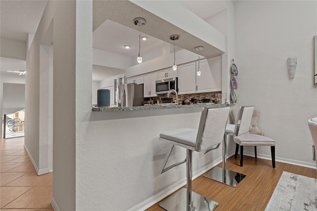 2026 Golfview Dr Unit 2026, Tarpon Springs, FL 34689 - kitchen with stainless steel appliances, white cabinetry, baseboards, and a breakfast bar