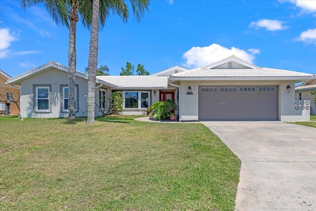 ranch-style home with stucco siding, an attached garage, concrete driveway, a tiled roof, and a front lawn