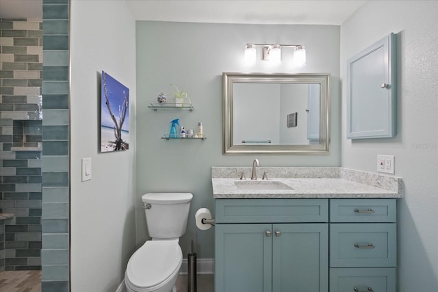 bathroom featuring toilet, vanity, and tiled shower