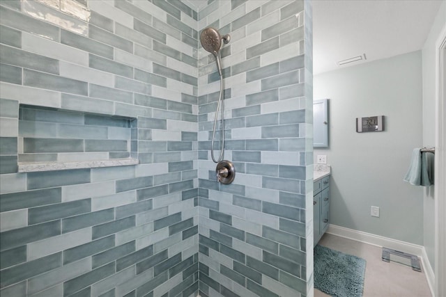 full bathroom with a tile shower, vanity, baseboards, and tile patterned floors