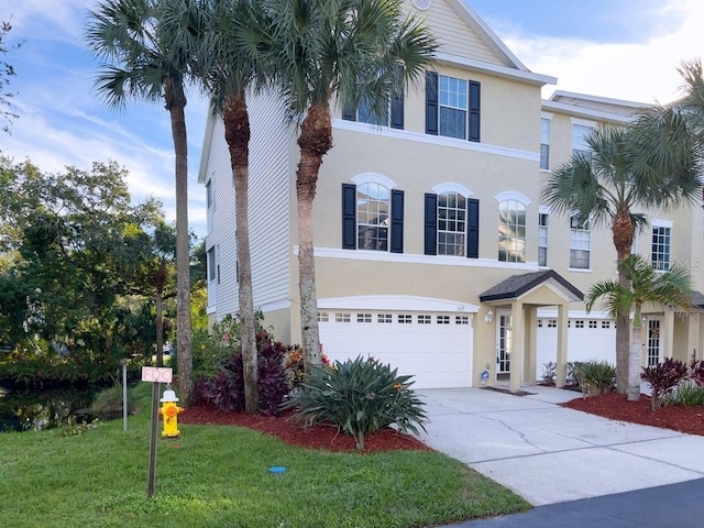 view of front of house with stucco siding, a garage, concrete driveway, and a front lawn