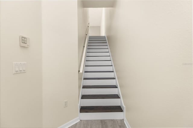 stairway with wood finished floors and baseboards