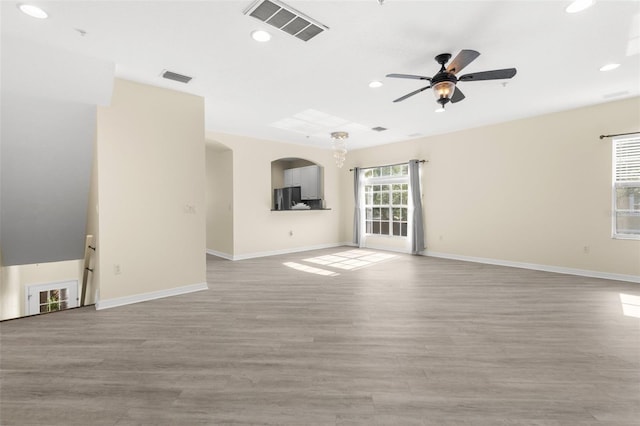 unfurnished living room featuring a ceiling fan, recessed lighting, baseboards, light wood finished floors, and arched walkways