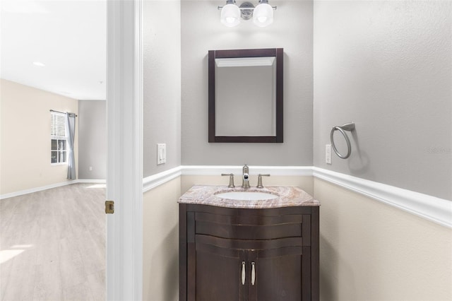 bathroom with vanity, wood finished floors, and baseboards