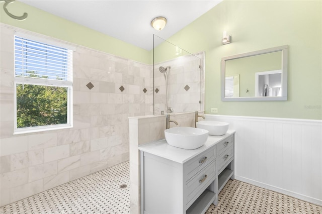 bathroom featuring a walk in shower, tile patterned floors, wainscoting, and double vanity
