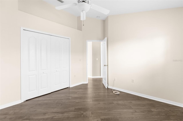 unfurnished bedroom featuring dark wood-style flooring, a closet, baseboards, and ceiling fan