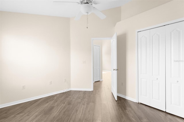 unfurnished bedroom with wood finished floors, baseboards, a closet, and a ceiling fan
